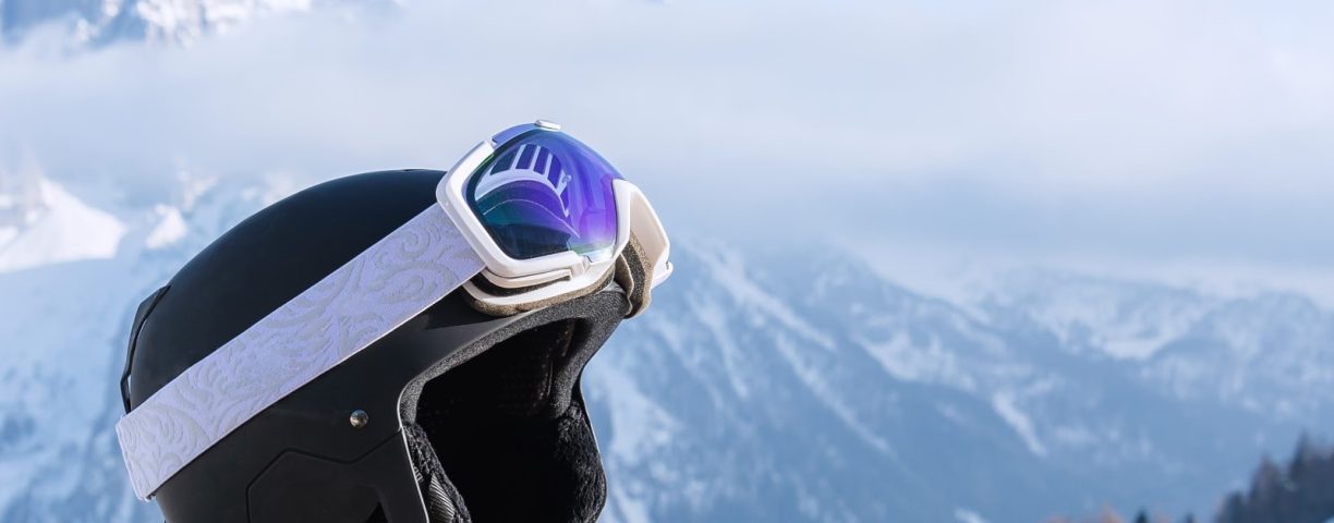 View of a ski helmet with sunglasses on the background of snow-capped mountains. Landscape, industry, sports concept